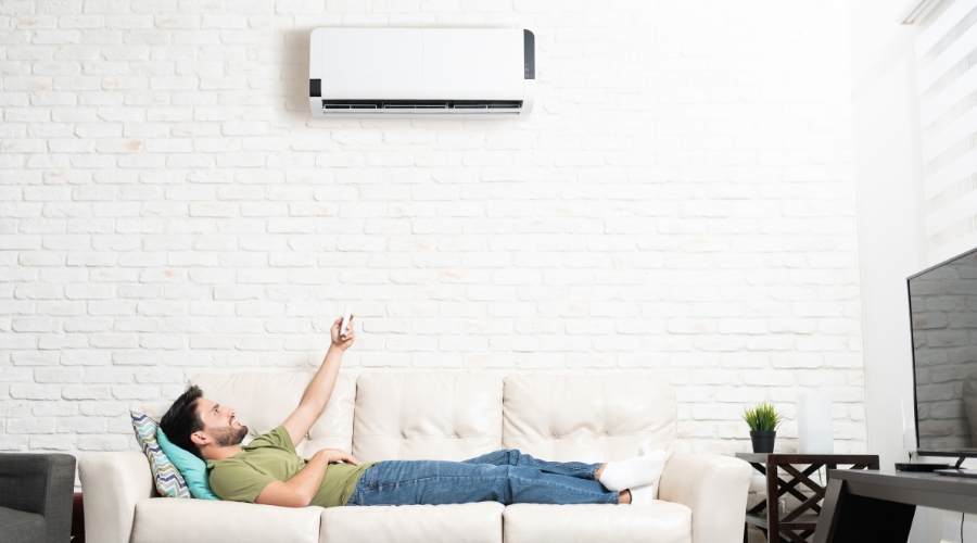 Man lounging on sofa, using air conditioner.
